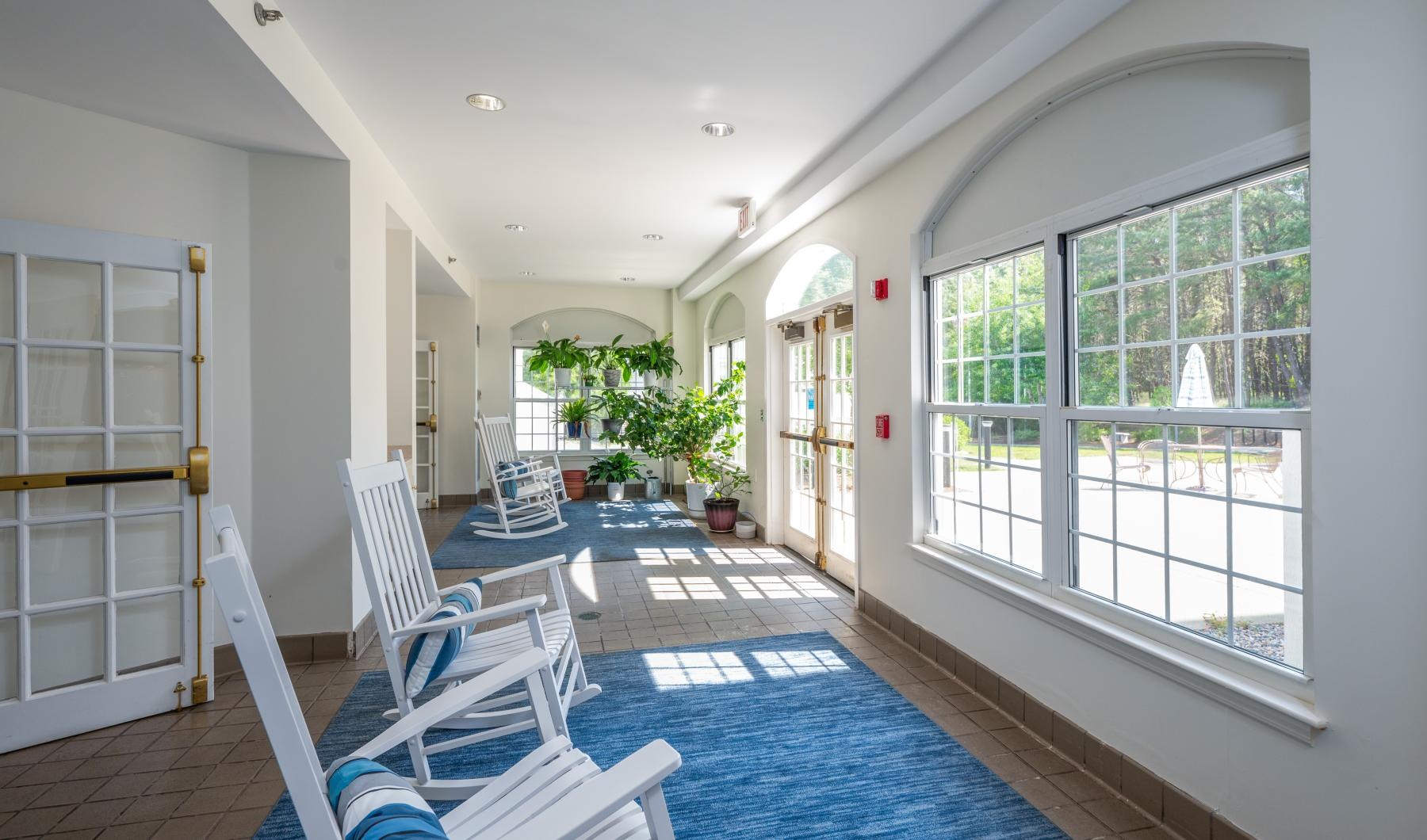 Settle into comfort at Serenity at Brewster a lounge area with rocking chairs and windows