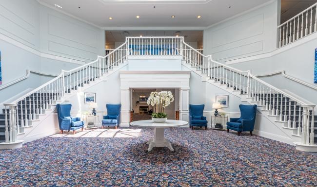 Settle into comfort at Serenity at Brewster the foyer of a building with a double staircase and chairs