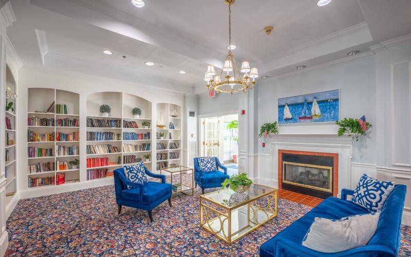 a clubroom with a book case, a couch and chairs